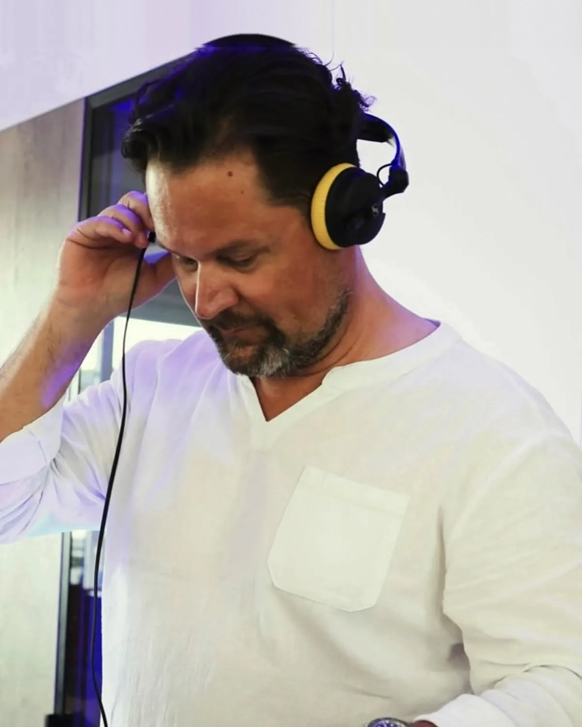DJ Jörg Ecke im weißen Hemd mit gelbem Kopfhörer am Pult