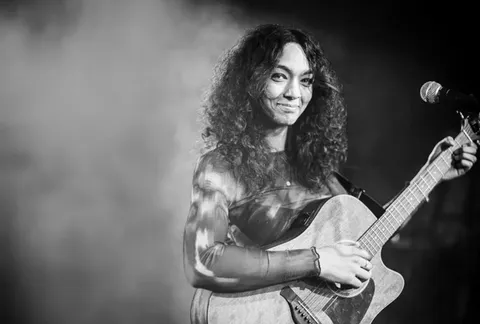 Lateesha Halmen mit Akustikgitarre am Mikrofon, Schwarz-Weiß-Aufnahme auf der Bühne
