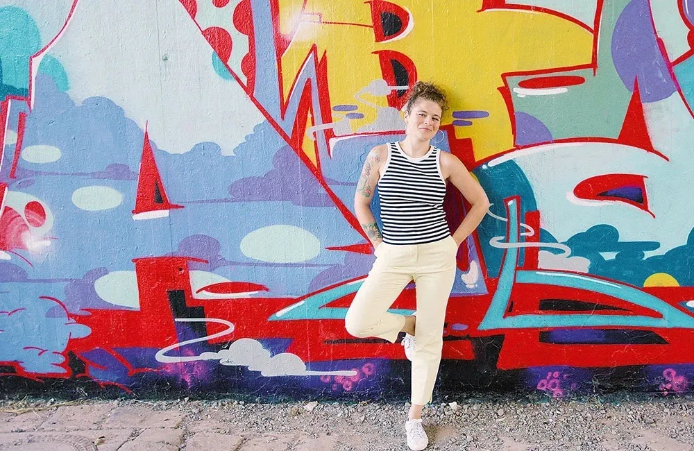 Lisa Knauer im gestreiften Top vor einer bunt besprühten Wand