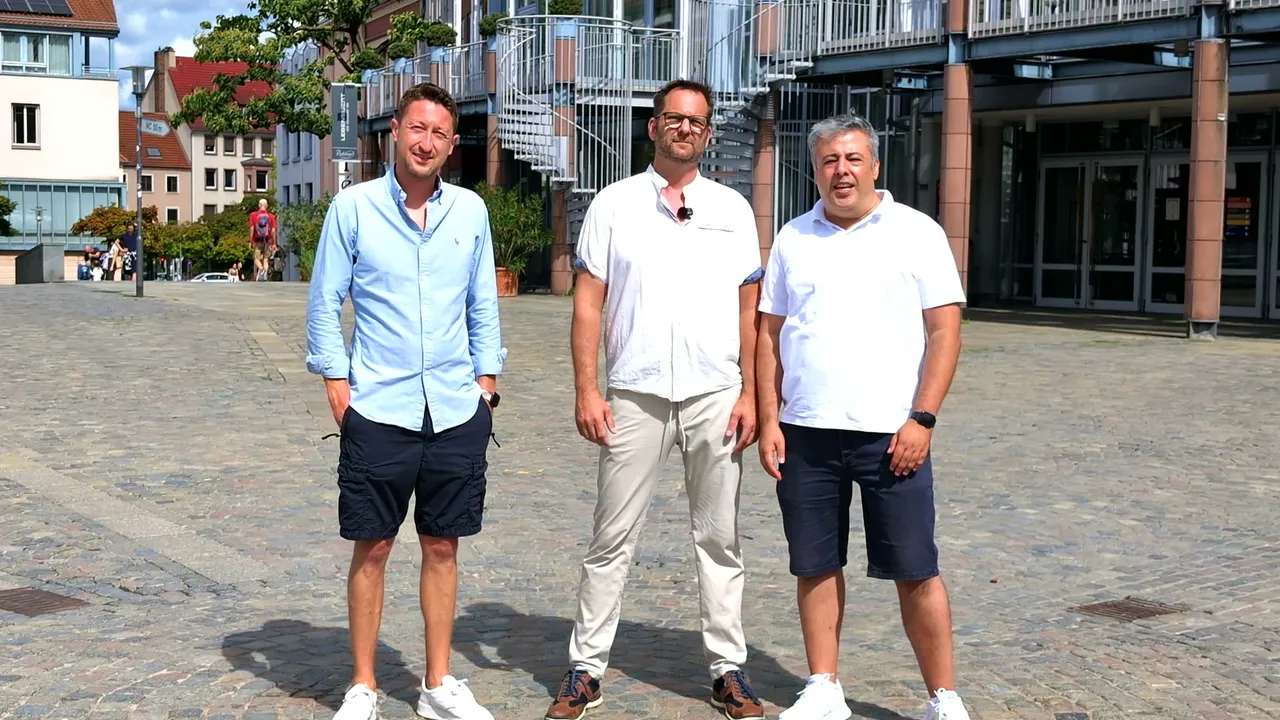 Christopher Maier, Jochen Grimm und Kassra Adloo stehen nebeneinander auf dem Schlossplatz vor der Stadthalle